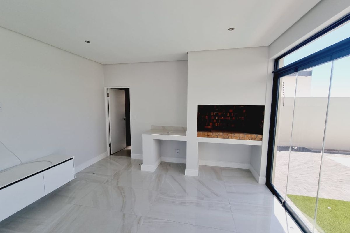 Modern enclosed patio featuring a built-in braai, prep sink with stone countertop, large format tiled flooring, and floor-to-ceiling sliding glass doors.