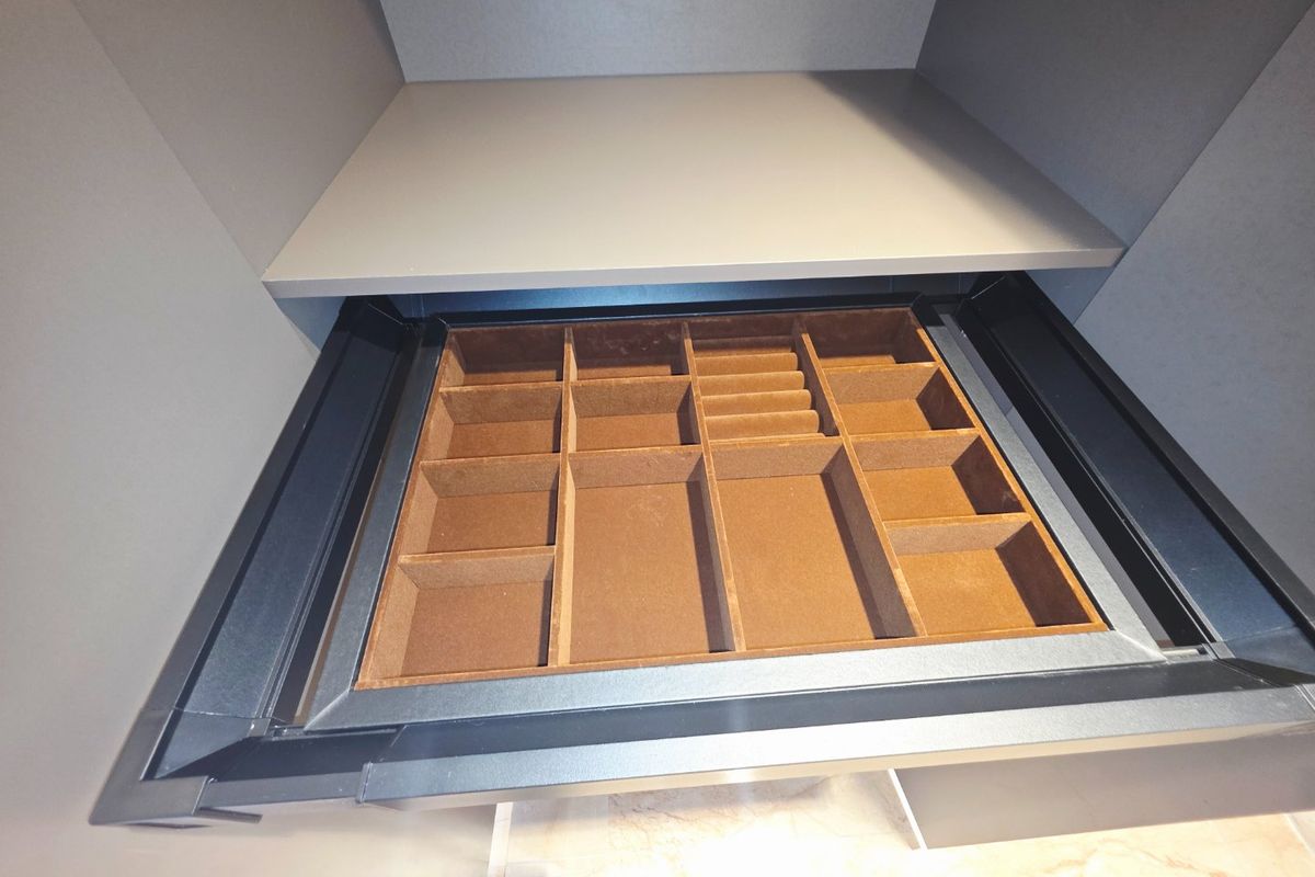 A close-up view of a high-quality built-in drawer organizer with velvet-lined compartments, integrated into modern bedroom cabinetry.