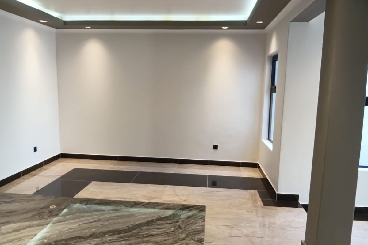 A bright, modern living area featuring high-end tiled flooring, recessed cove lighting, and a sleek stone-topped island or counter.