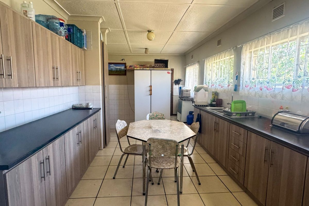 A functional kitchen featuring laminate cabinetry, dark countertops, tiled flooring, and a tiled backsplash, offering a practical layout for daily meal preparation.