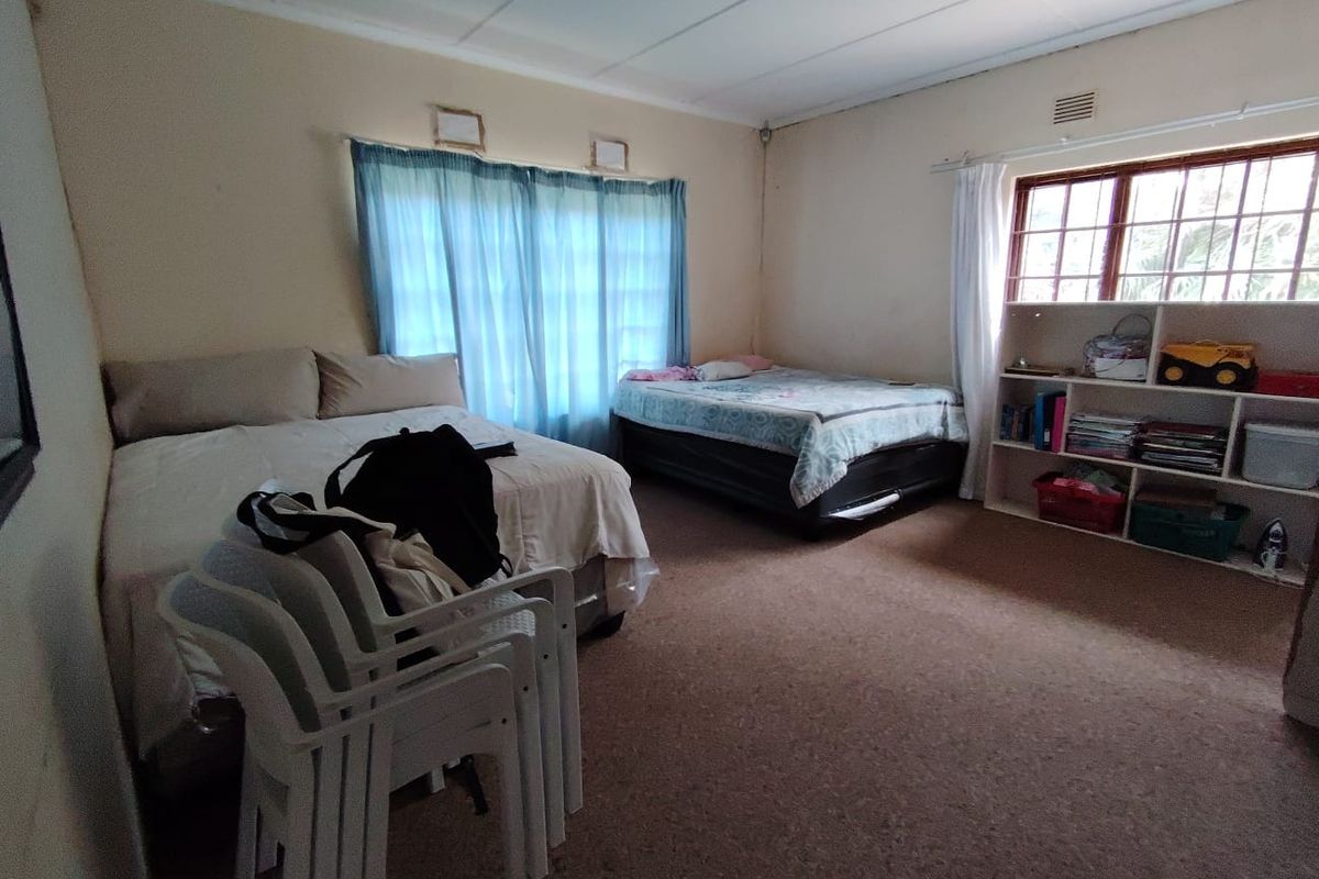 Spacious bedroom featuring built-in shelving, security bars on windows, and a ceiling fan, with carpeted flooring throughout.