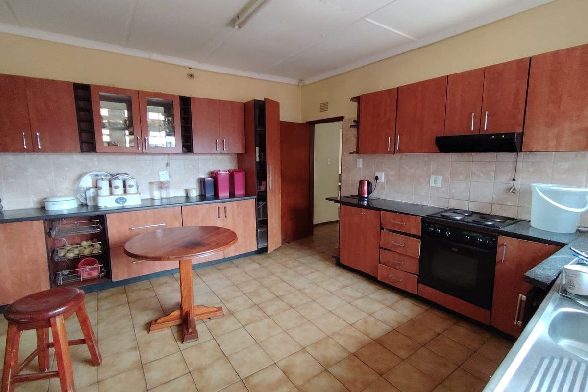 A functional kitchen featuring laminate cabinetry, granite countertops, built-in oven, electric hob, and ceramic tile flooring, offering a practical layout for daily use.