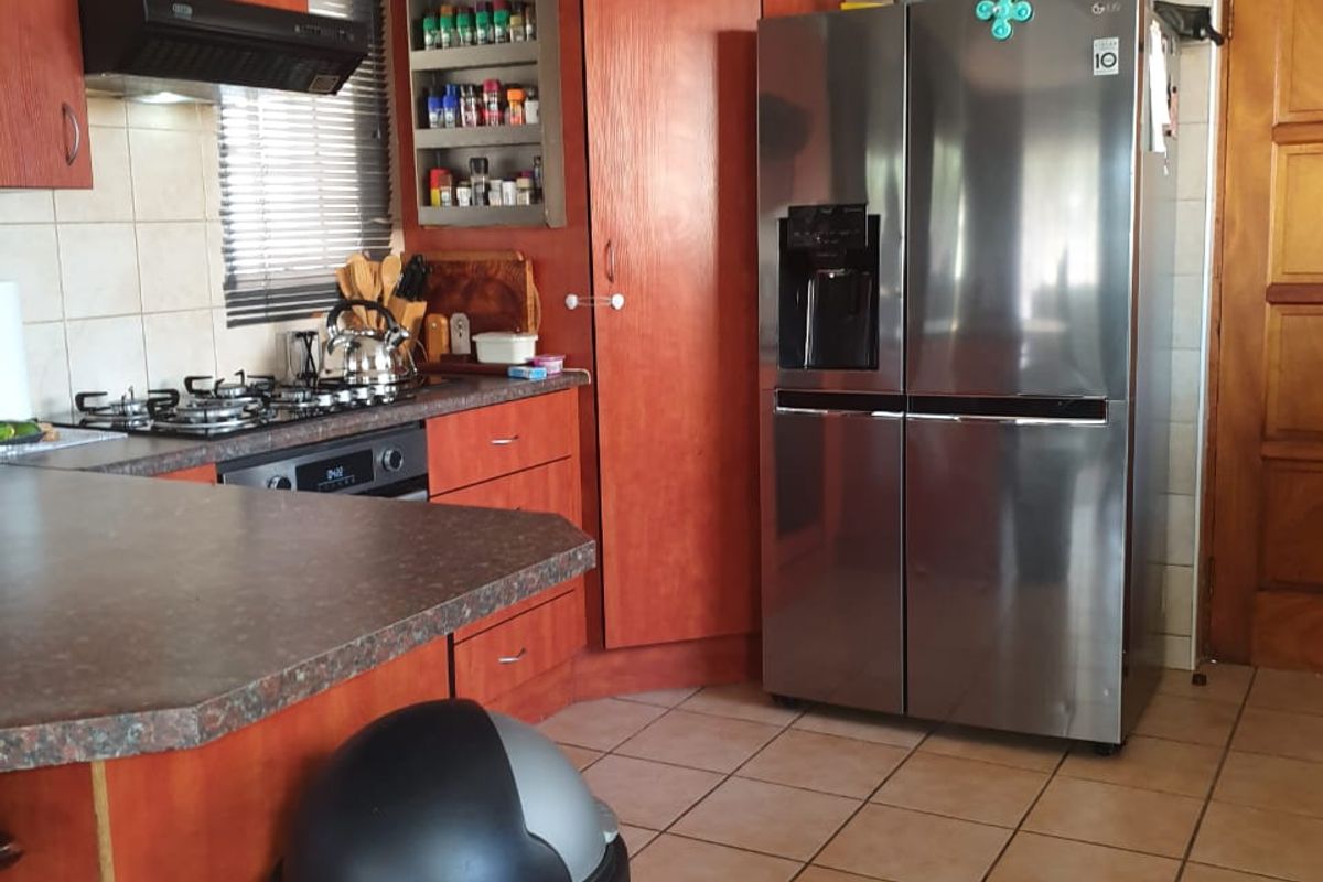 A functional kitchen featuring wood-tone cabinetry, tiled backsplash, gas hob, and integrated oven, offering a practical layout with ample storage space.