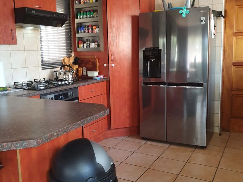 A functional kitchen featuring wood-tone cabinetry, tiled backsplash, gas hob, and integrated oven, offering a practical layout with ample storage space.