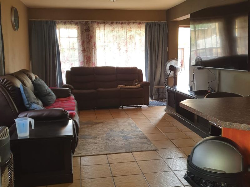 A living room featuring ceramic floor tiles, flush mount ceiling lighting, and a sliding glass door providing access to the exterior.