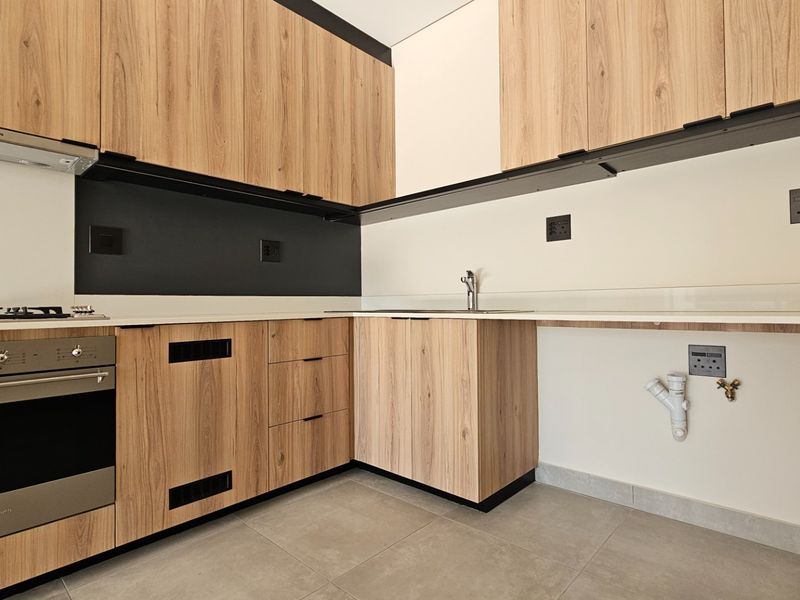 Modern kitchen featuring wood-look cabinetry, stone countertops, built-in oven, gas hob, and dedicated plumbing connections for appliances.