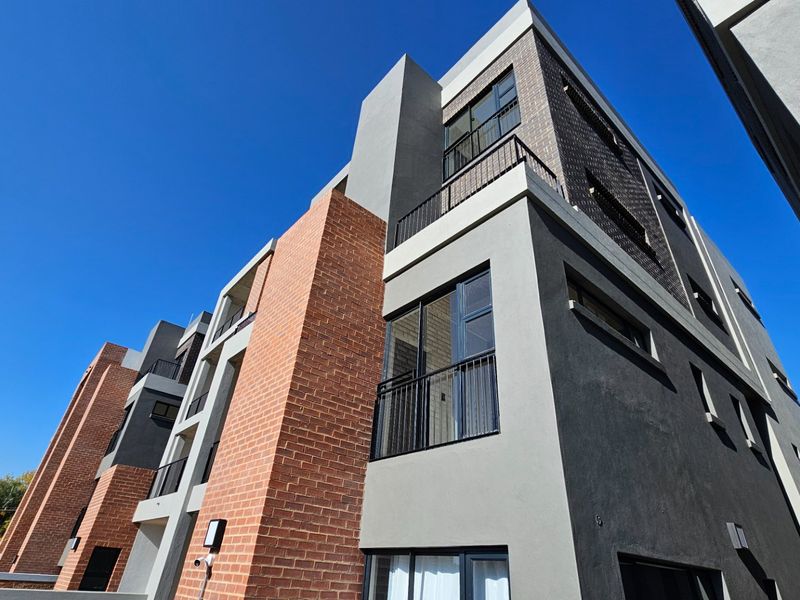Modern multi-story townhouse exterior featuring a contemporary mix of brick and rendered finishes with integrated balconies and large aluminium-framed windows.