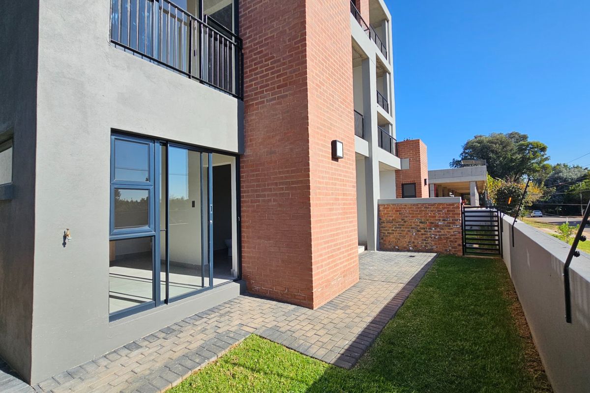 Rear view of the townhouse featuring a paved patio area, small private lawn, and sliding door access to the interior living space.