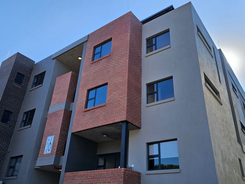 Modern multi-story townhouse block featuring a contemporary mix of face brick and plastered exterior finishes with aluminium window frames.