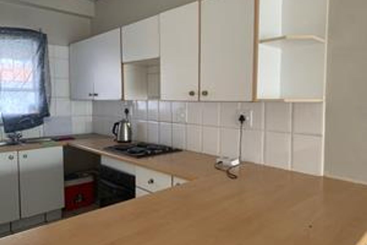 A functional kitchen featuring laminate countertops, built-in cabinetry, a tiled backsplash, and integrated cooking appliances.