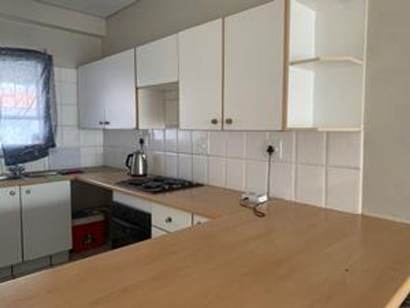 A functional kitchen featuring laminate countertops, built-in cabinetry, a tiled backsplash, and integrated cooking appliances.