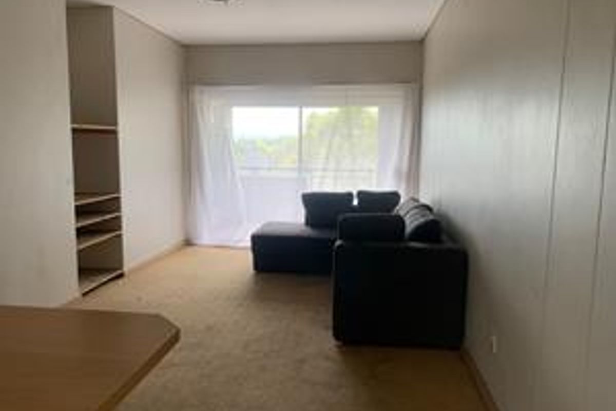 A living room featuring built-in shelving, carpet flooring, and a sliding glass door leading to an outdoor area.