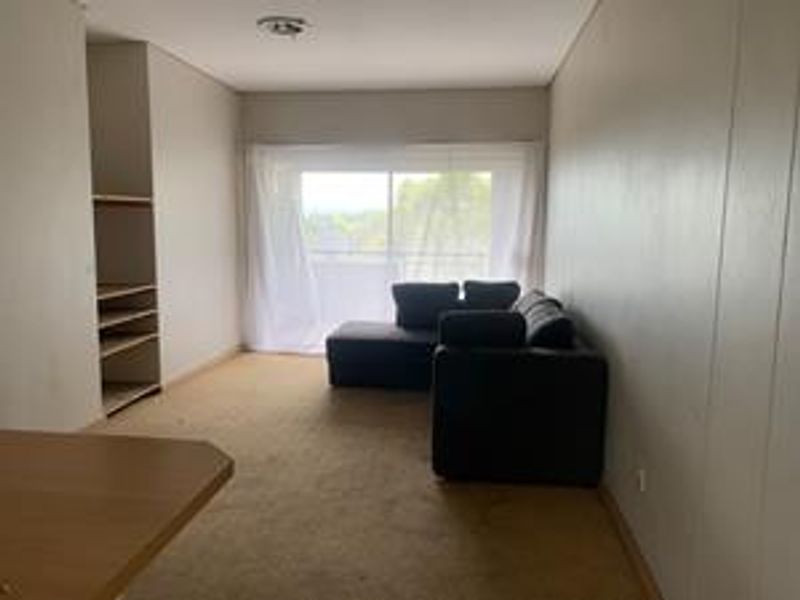 A living room featuring built-in shelving, carpet flooring, and a sliding glass door leading to an outdoor area.