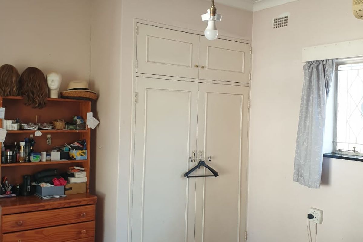 A bedroom featuring a built-in wardrobe, air conditioning unit, and carpet flooring, requiring cosmetic updates to improve its overall condition.