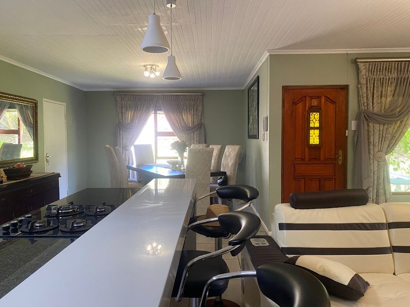 Open plan living and dining area featuring a breakfast bar with integrated gas hob, tongue and groove ceiling, and direct access to the entrance.