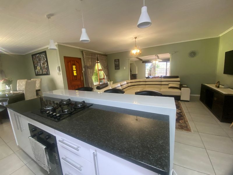 Spacious open-plan living area featuring a modern kitchen island with gas hob, granite countertops, and tiled flooring throughout the combined kitchen and lounge space.