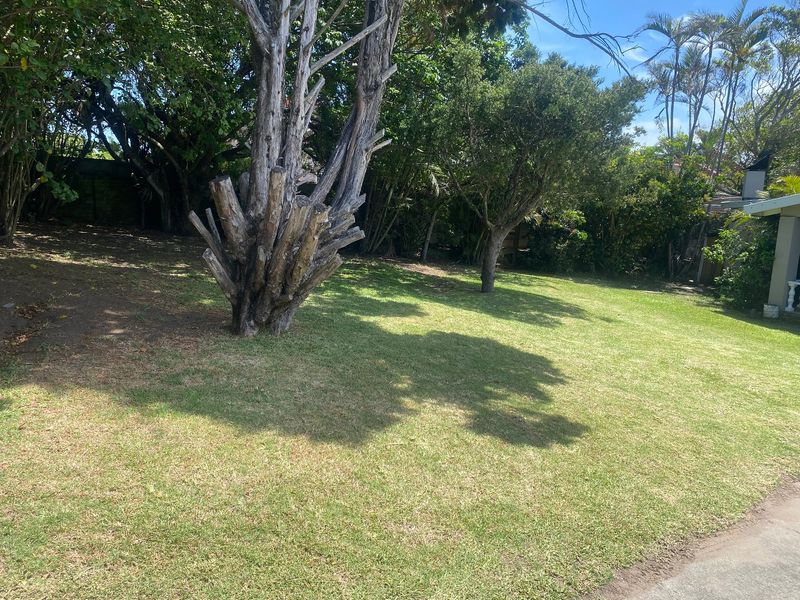 A spacious, well-maintained garden area featuring established mature trees and a large lawn, providing a private outdoor setting.