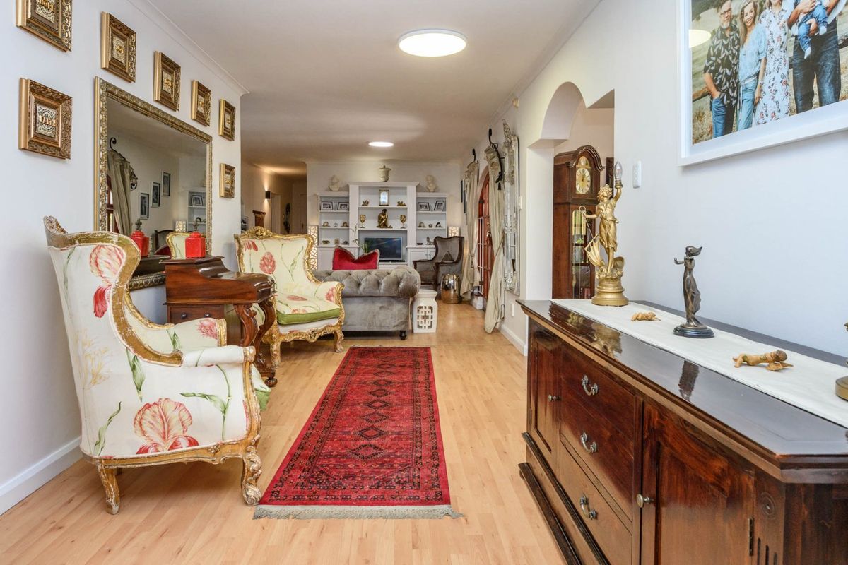 A spacious living area featuring light laminate flooring, built-in shelving units, and a decorative archway leading to adjacent spaces.