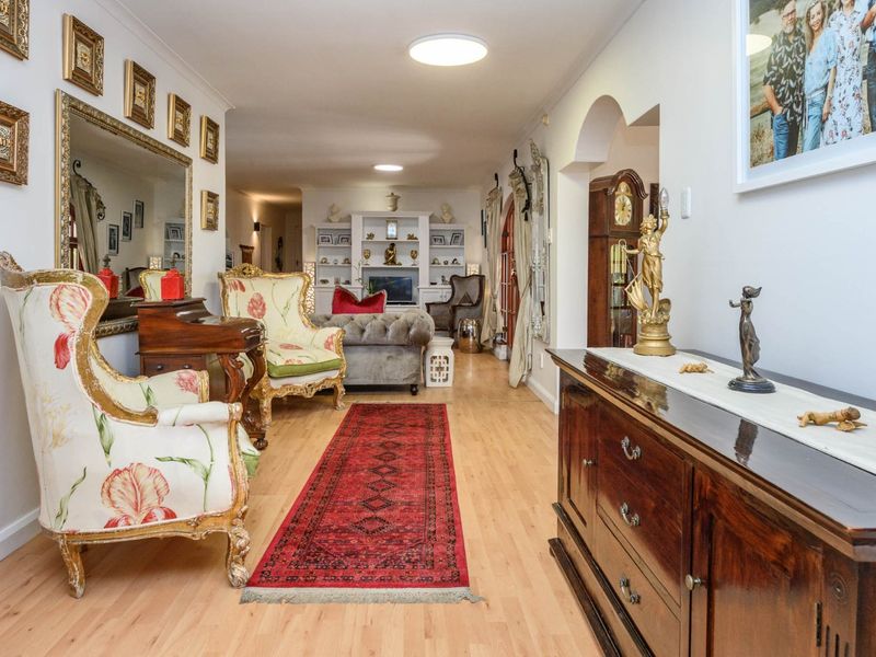A spacious living area featuring light laminate flooring, built-in shelving units, and a decorative archway leading to adjacent spaces.