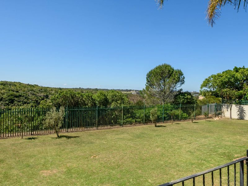 A well-maintained garden featuring a manicured lawn, secure metal perimeter fencing, and scenic views of the surrounding natural landscape.