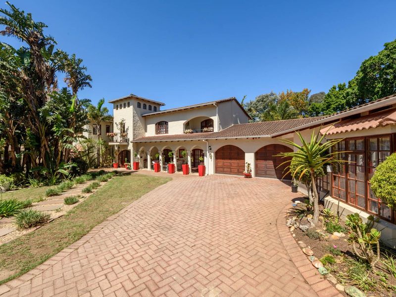 A well-maintained Mediterranean-style house featuring a brick-paved driveway, double garage, and an inviting arched covered walkway set within a lush garden.