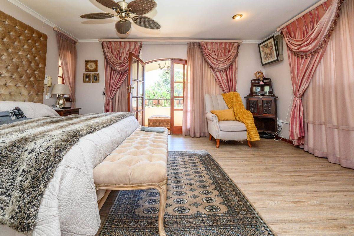 Spacious bedroom featuring laminate flooring, a ceiling fan, and direct access to an outdoor balcony through classic french doors.
