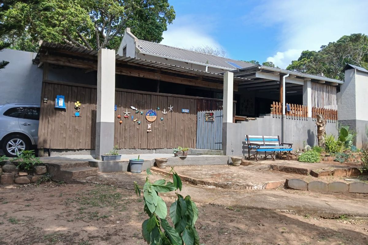 Rear exterior view of the townhouse featuring a covered patio area, timber cladding, and a concrete patio surface set within a garden space.