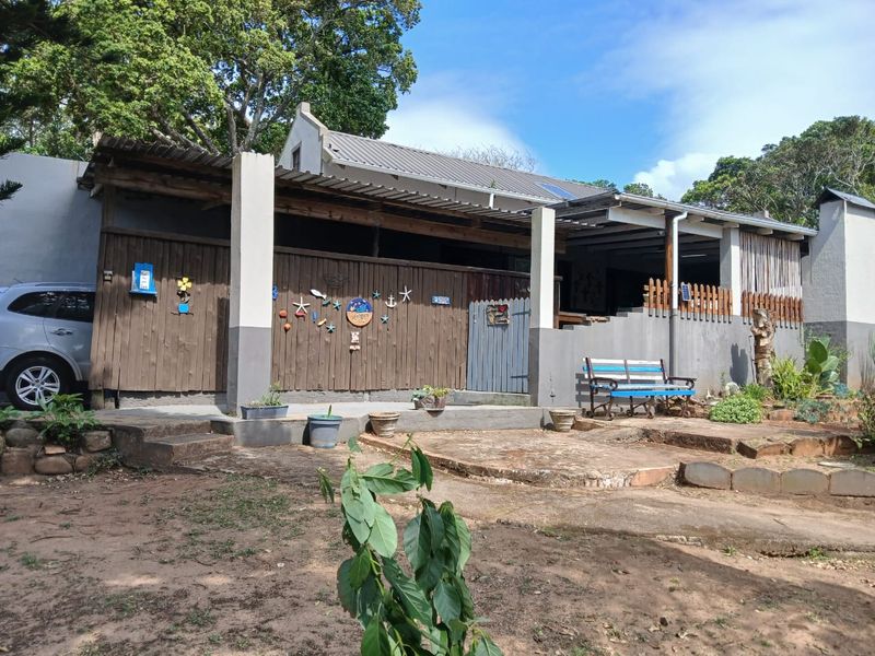 Rear exterior view of the townhouse featuring a covered patio area, timber cladding, and a concrete patio surface set within a garden space.