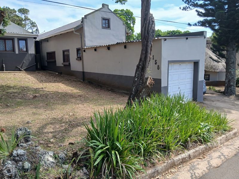 Front exterior view of a townhouse featuring a garage, gabled roofline, and established garden area.