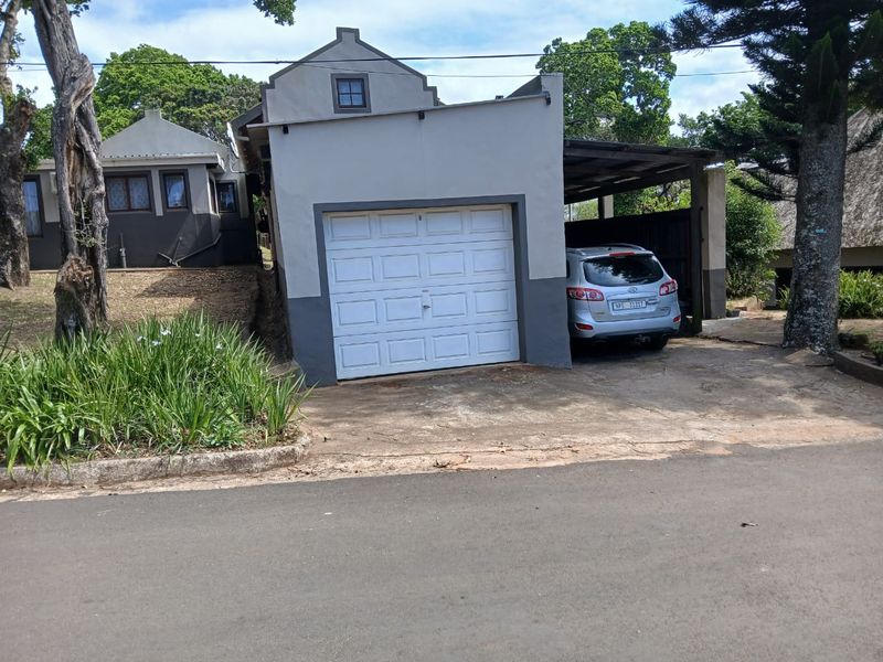 Front exterior view of the townhouse featuring a single garage door, an attached carport, and a concrete driveway.