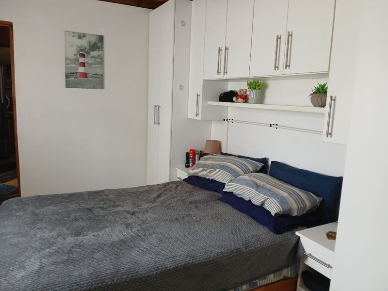 A bedroom featuring white built-in cupboards and overhead storage cabinets providing ample storage space.