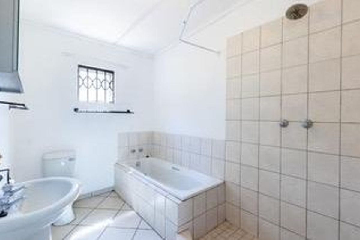 A functional bathroom featuring a pedestal basin, a built-in bathtub, and a tiled shower area with a wall-mounted shower head.