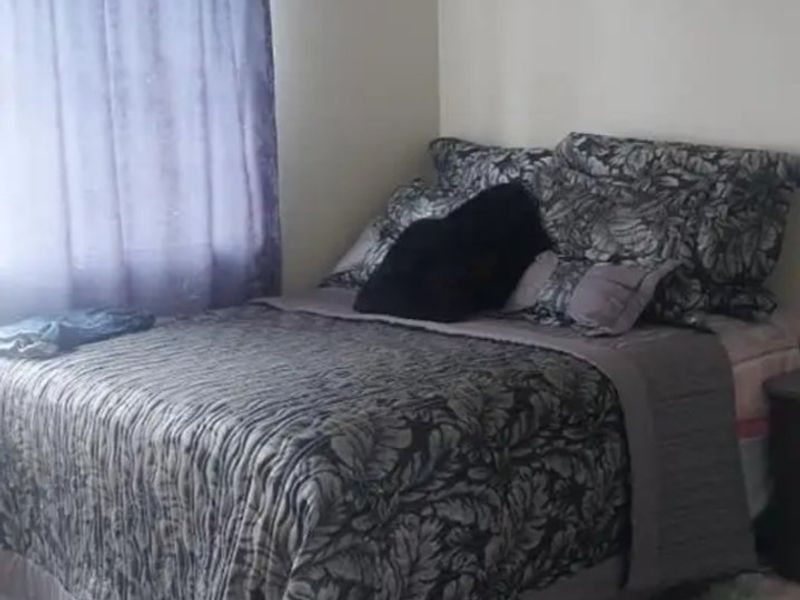 A standard bedroom featuring neutral wall finishes and a window with a curtain rod.