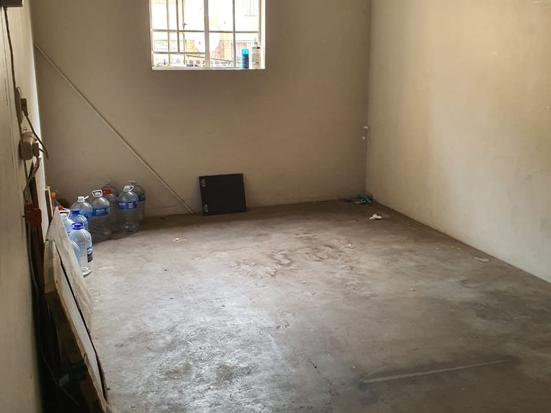 An empty garage space featuring a concrete floor and a security window, requiring maintenance and cosmetic updates.