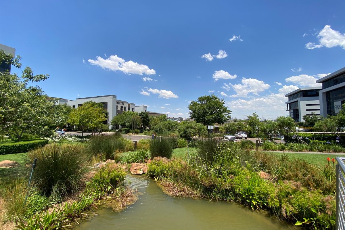 A well-maintained commercial office park featuring landscaped gardens, a central water feature, and modern office buildings in a professional business environment.