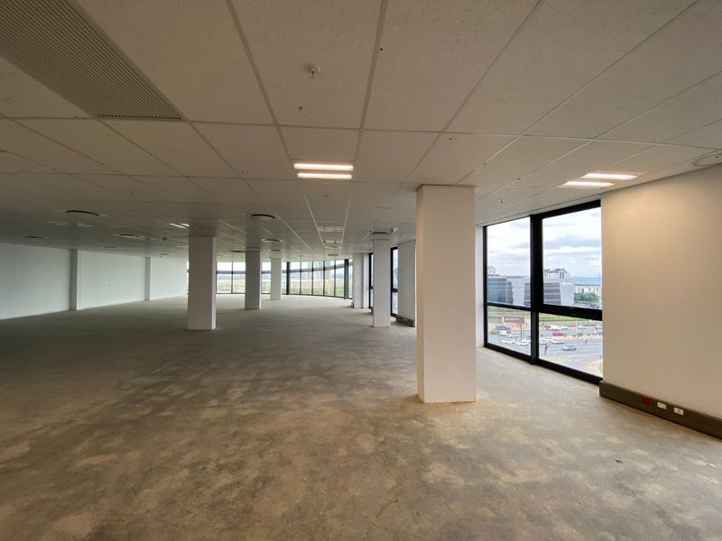 Spacious open-plan commercial office space featuring large floor-to-ceiling windows, suspended ceilings, and structural columns, ready for custom flooring and fit-out.