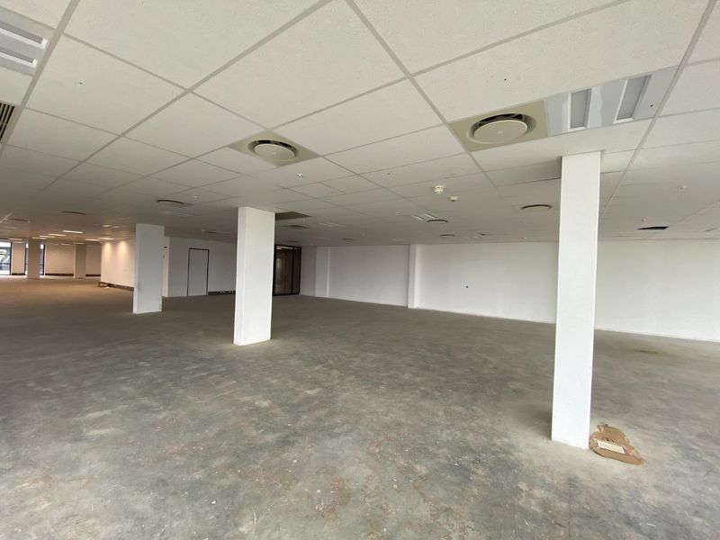 A large, vacant open-plan commercial space featuring a suspended ceiling, recessed air conditioning, and structural columns, ready for custom fit-out.