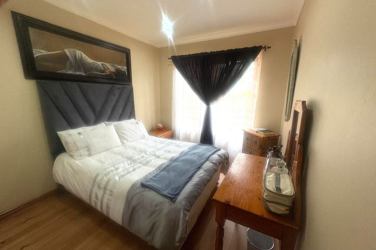 A cozy bedroom featuring laminate flooring and a window with a curtain rod, providing a comfortable and functional sleeping space.