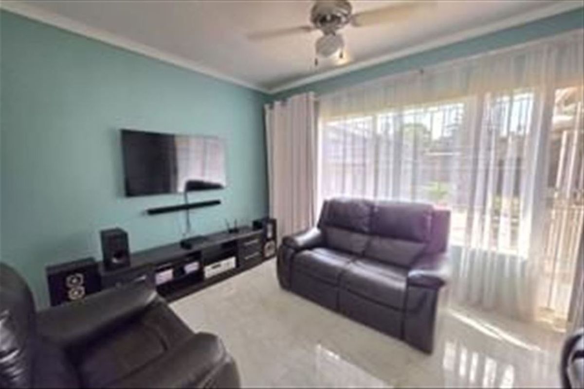 A comfortable living room featuring tiled flooring, a ceiling fan, and a large sliding glass door providing access to the exterior.