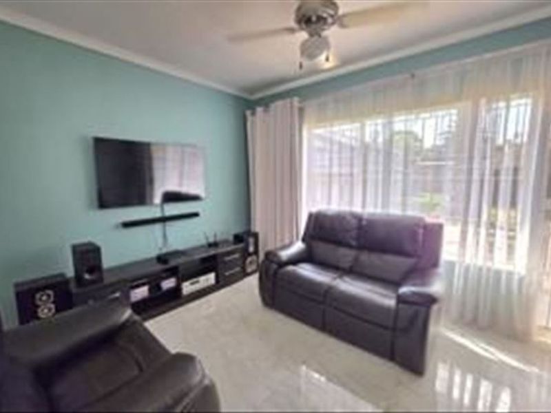 A comfortable living room featuring tiled flooring, a ceiling fan, and a large sliding glass door providing access to the exterior.