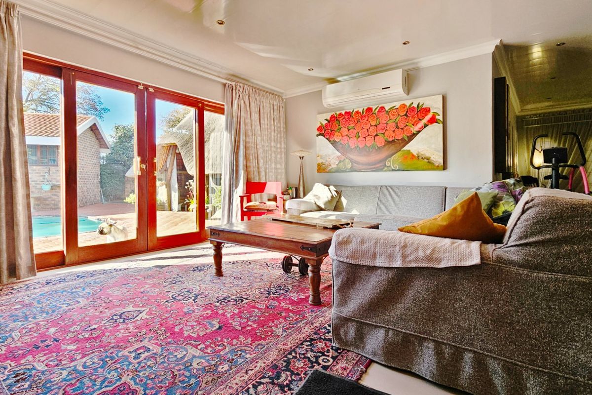 A bright living room featuring large wooden sliding doors that open onto a patio and pool area, complemented by a wall-mounted air conditioning unit.