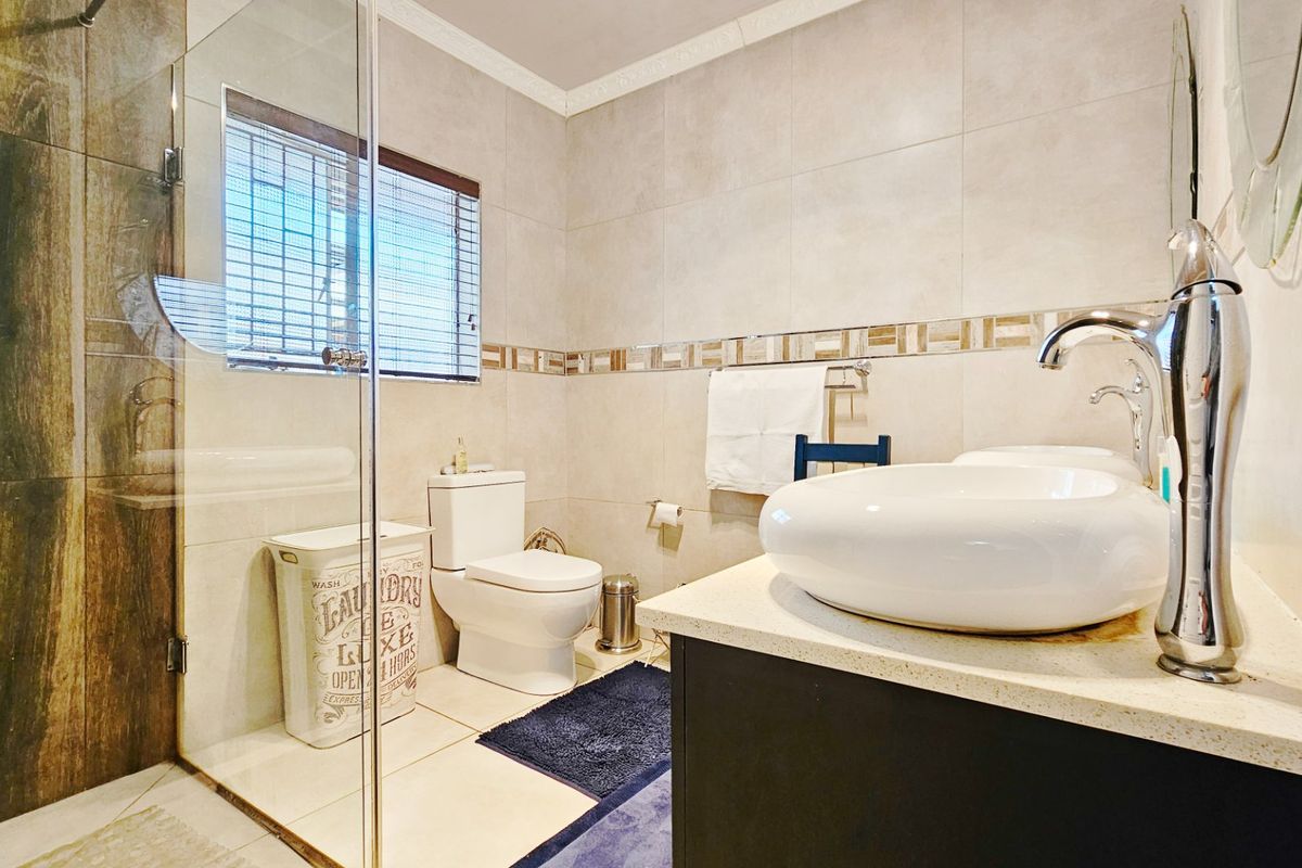 Modern bathroom featuring a glass-enclosed shower, contemporary vessel sink on a vanity, and neutral wall tiling.