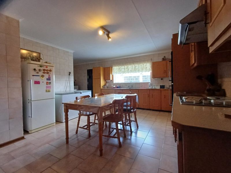 Spacious kitchen featuring wooden cabinetry, tiled finishes, and a built-in hob with extractor fan, offering a functional layout with space for a dining area.