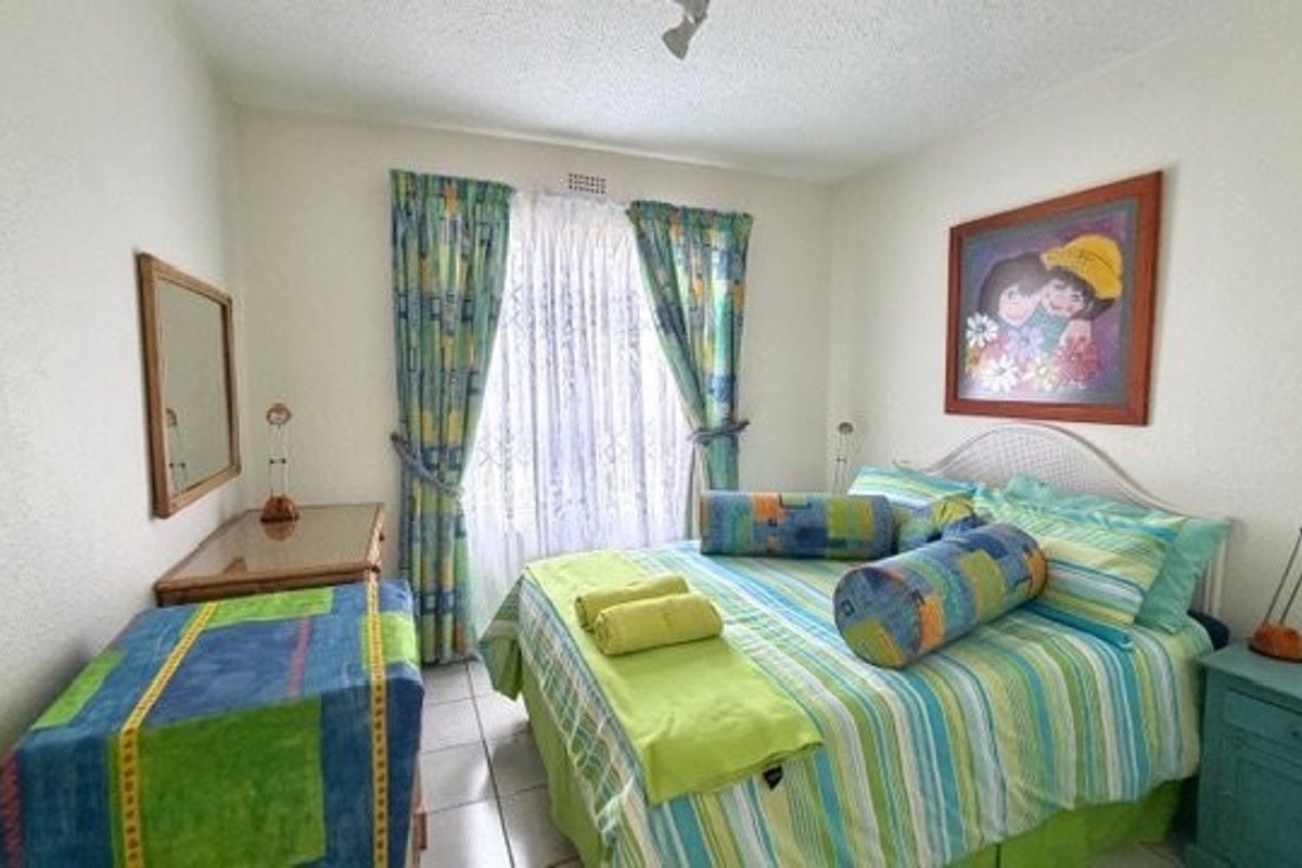 A functional bedroom featuring tiled flooring and a window with curtains, providing a comfortable and well-lit sleeping space.