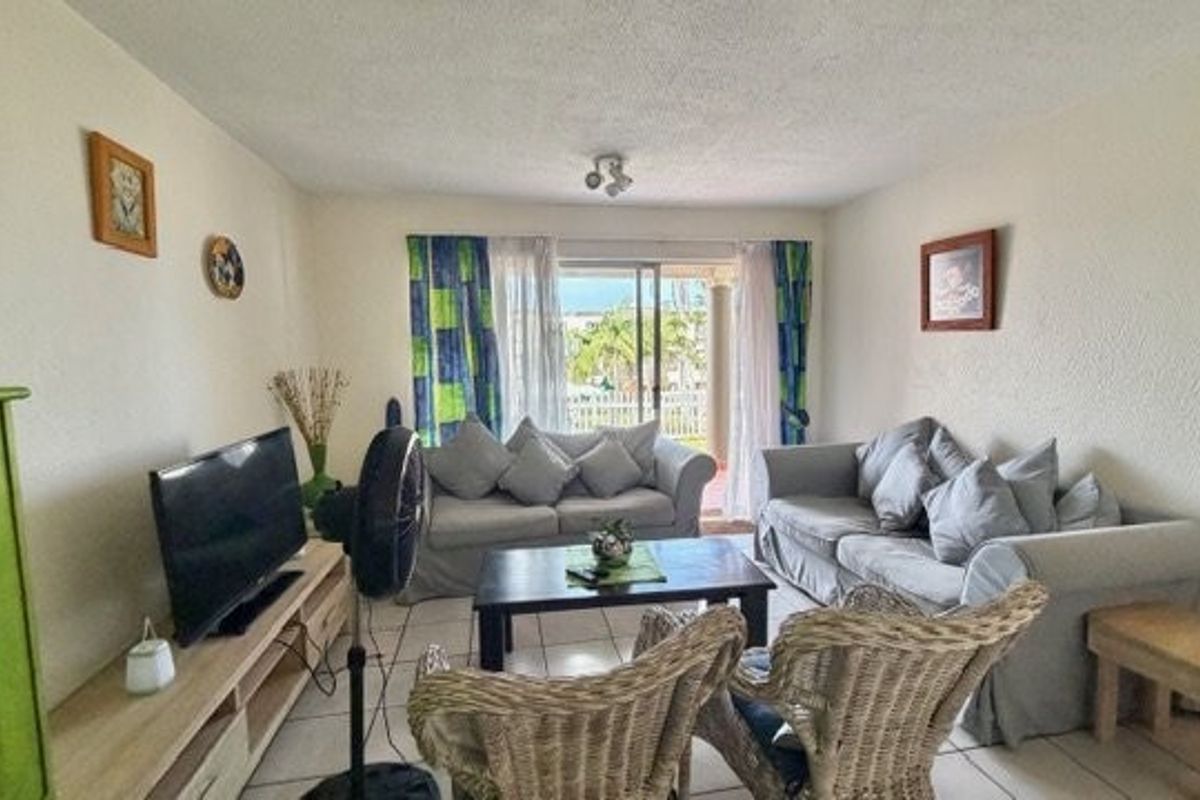A comfortable living room featuring tiled flooring and a sliding glass door that provides access to an outdoor patio area.
