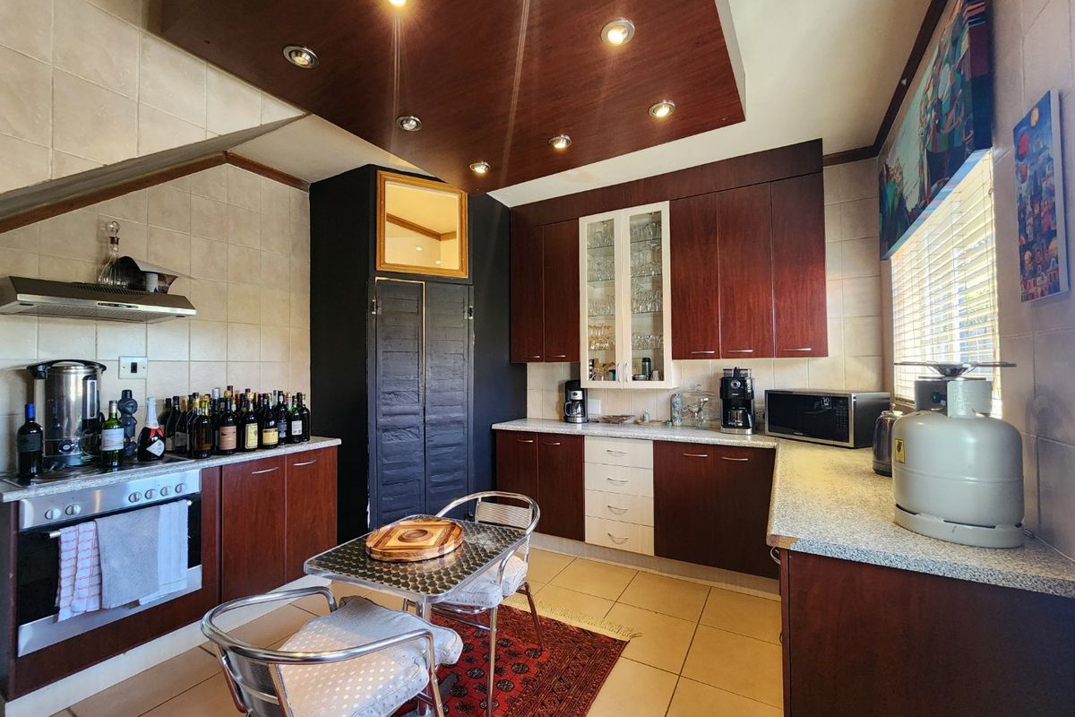 A functional kitchen featuring dark wood cabinetry, a built-in oven with extractor fan, tiled flooring, and a dedicated breakfast nook area.