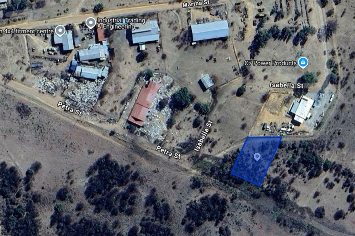 Aerial view of a vacant residential plot located in a semi-industrial area, highlighting the property boundaries and surrounding street access.