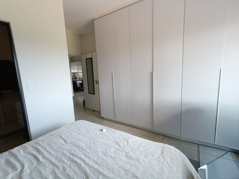 A bedroom featuring floor-to-ceiling built-in cupboards and neutral tiled flooring, offering a clean and functional space.