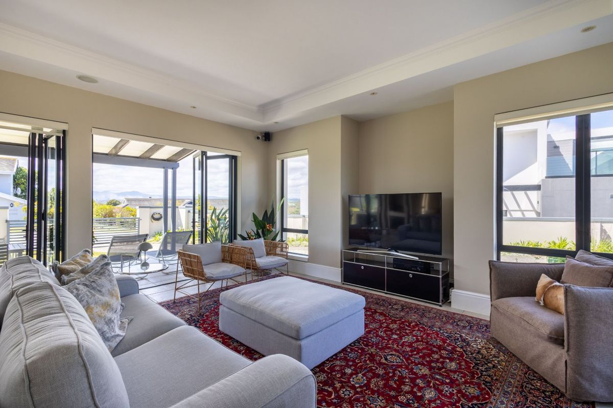 Spacious living room featuring large bi-fold doors opening onto a covered patio, recessed ceiling lighting, and neutral wall finishes.
