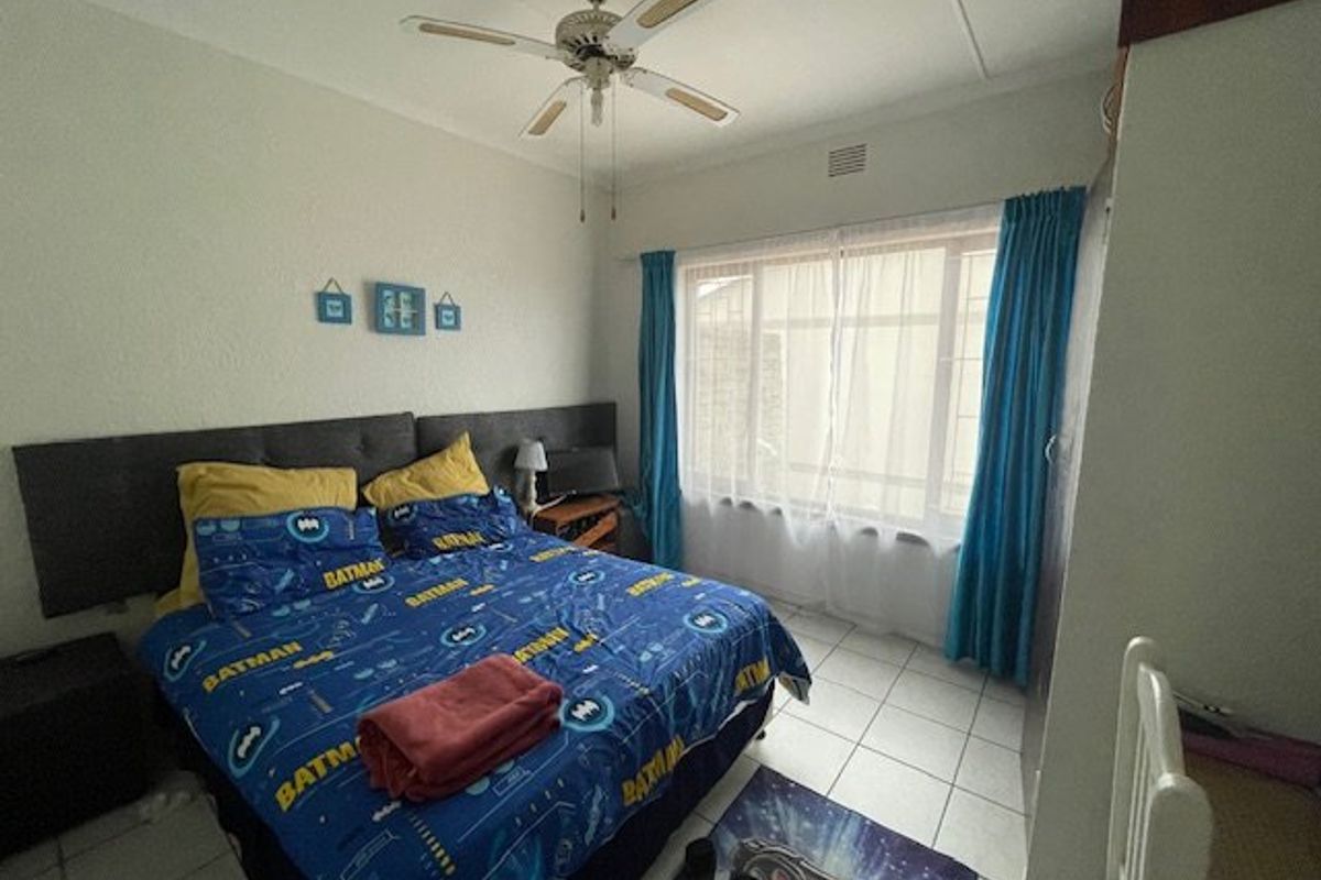 A functional bedroom featuring tiled flooring, a ceiling fan, and built-in storage, offering a comfortable and practical living space.